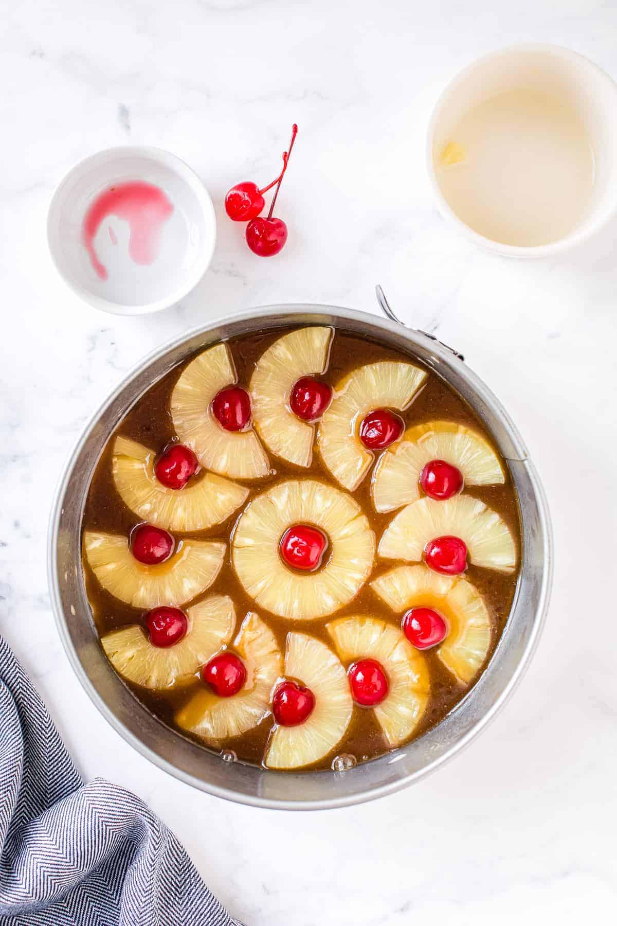 Maraschino cherries and pineapple slices on the bottom of cake pan for cake