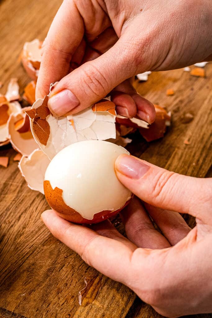 Hands peeling shell off hard boiled egg