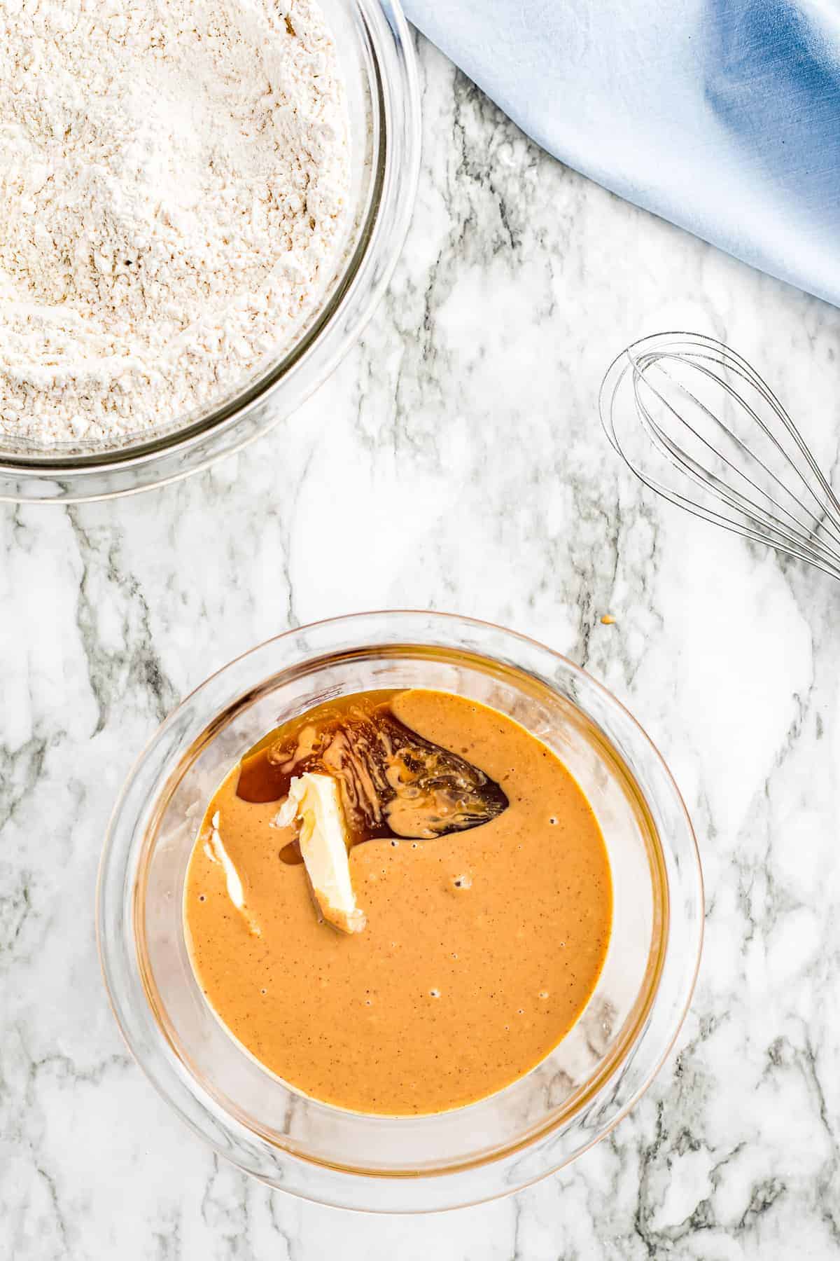 Overhead image of glass bowl with ingredients peanut butter mixture for cookies