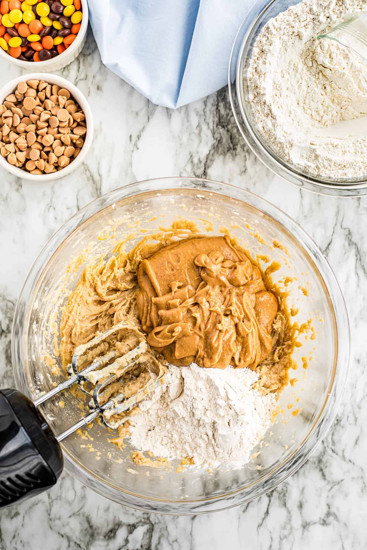 Hand mixer combining ingredients for peanut butter cookie dough