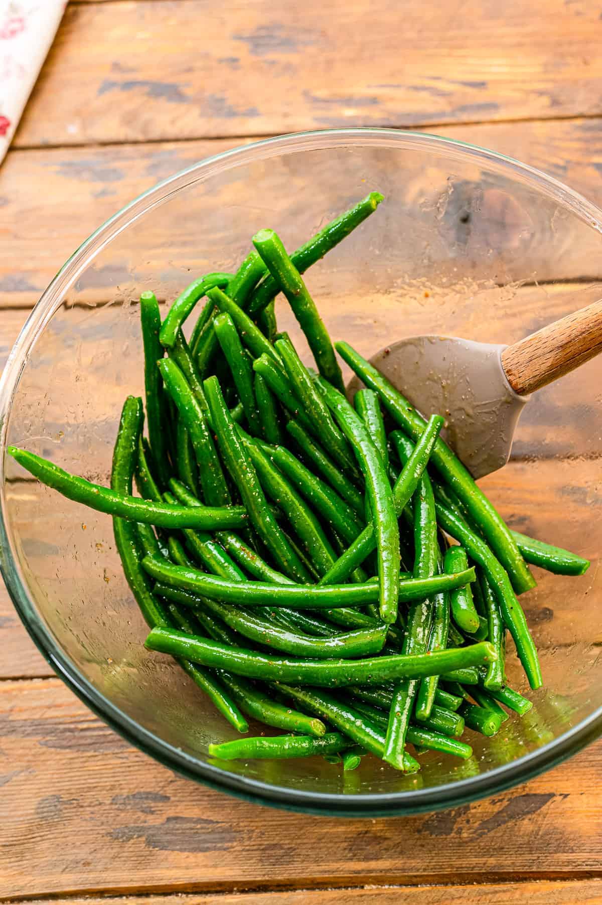 Mixing green beans in glass bowl with seasonings