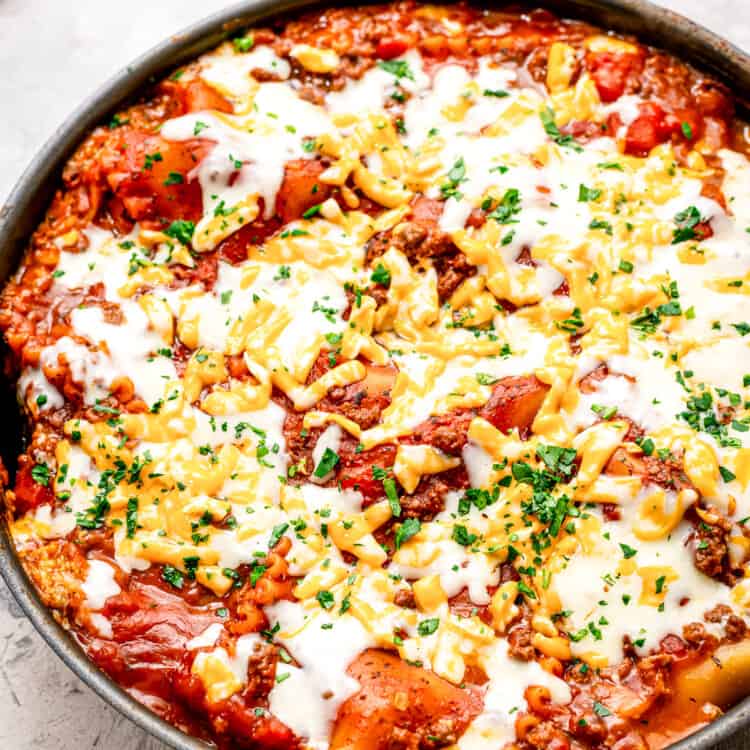 A skillet with lasagna in it topped with cheese