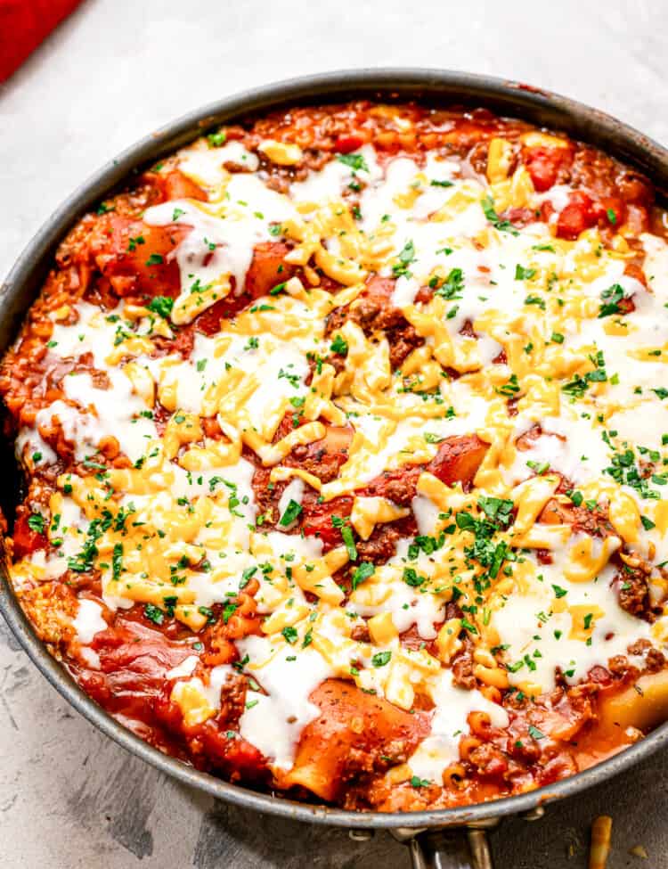 A skillet with lasagna in it topped with cheese