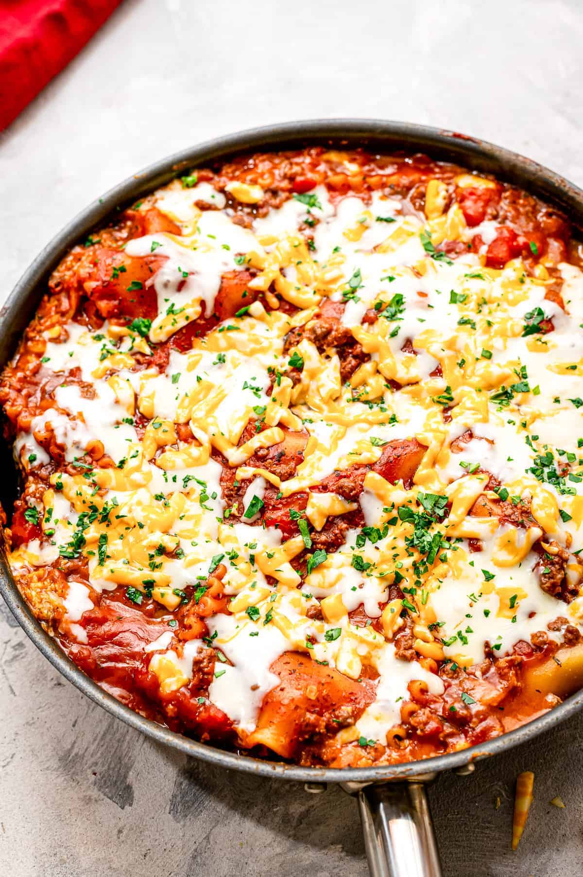 A skillet with lasagna in it topped with cheese