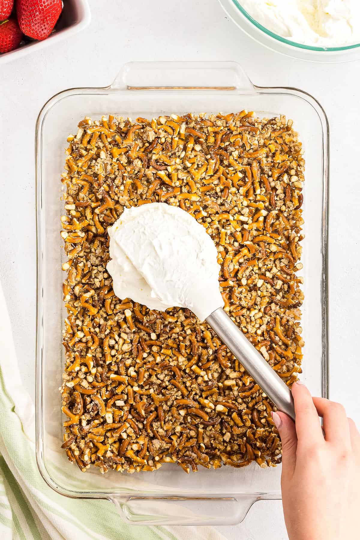 Spreading cream cheese filling over pretzel crust