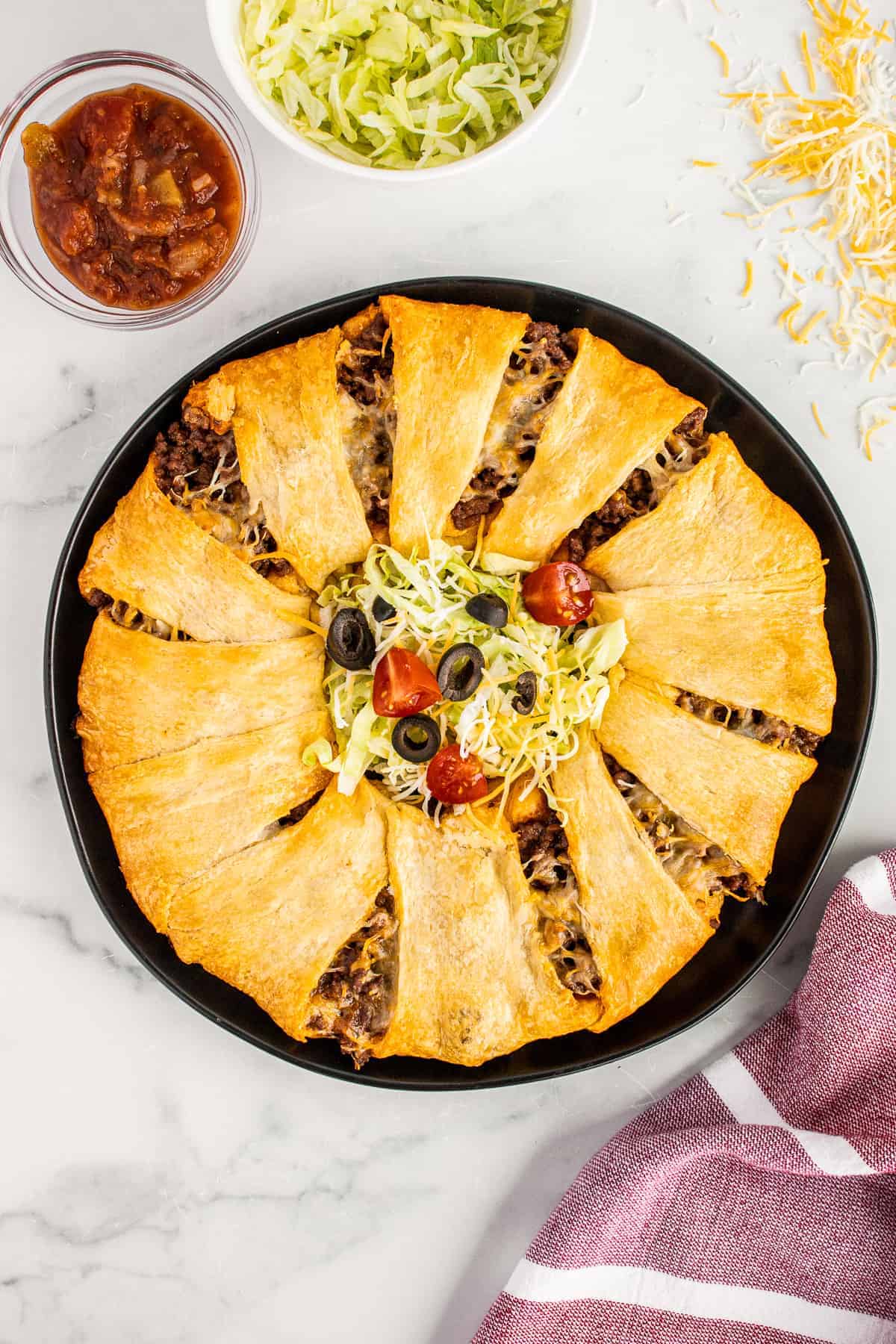Overhead image baked taco crescent ring with taco toppings in middle
