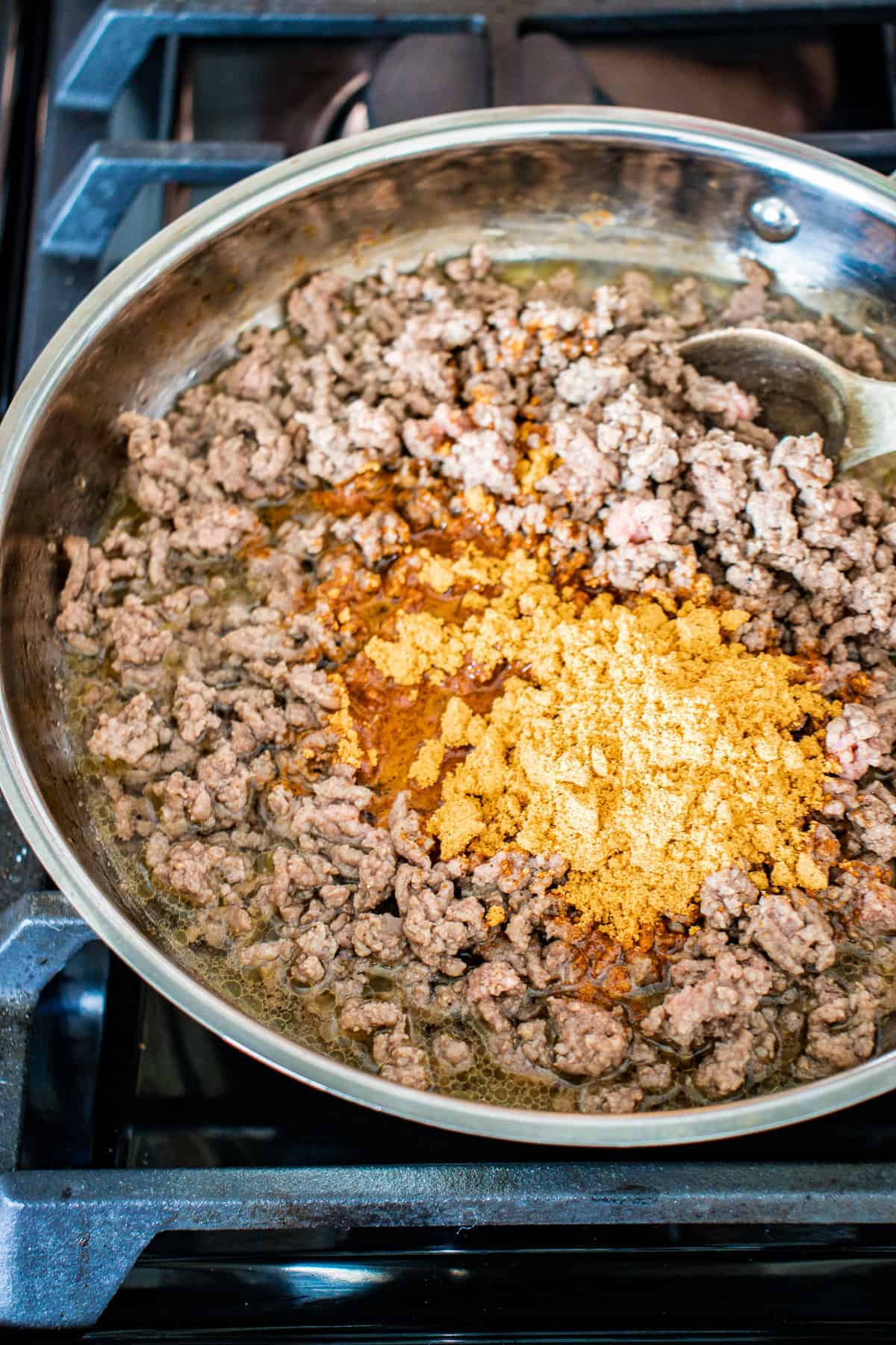 Skillet with browned ground beef and taco seasoning before mixing