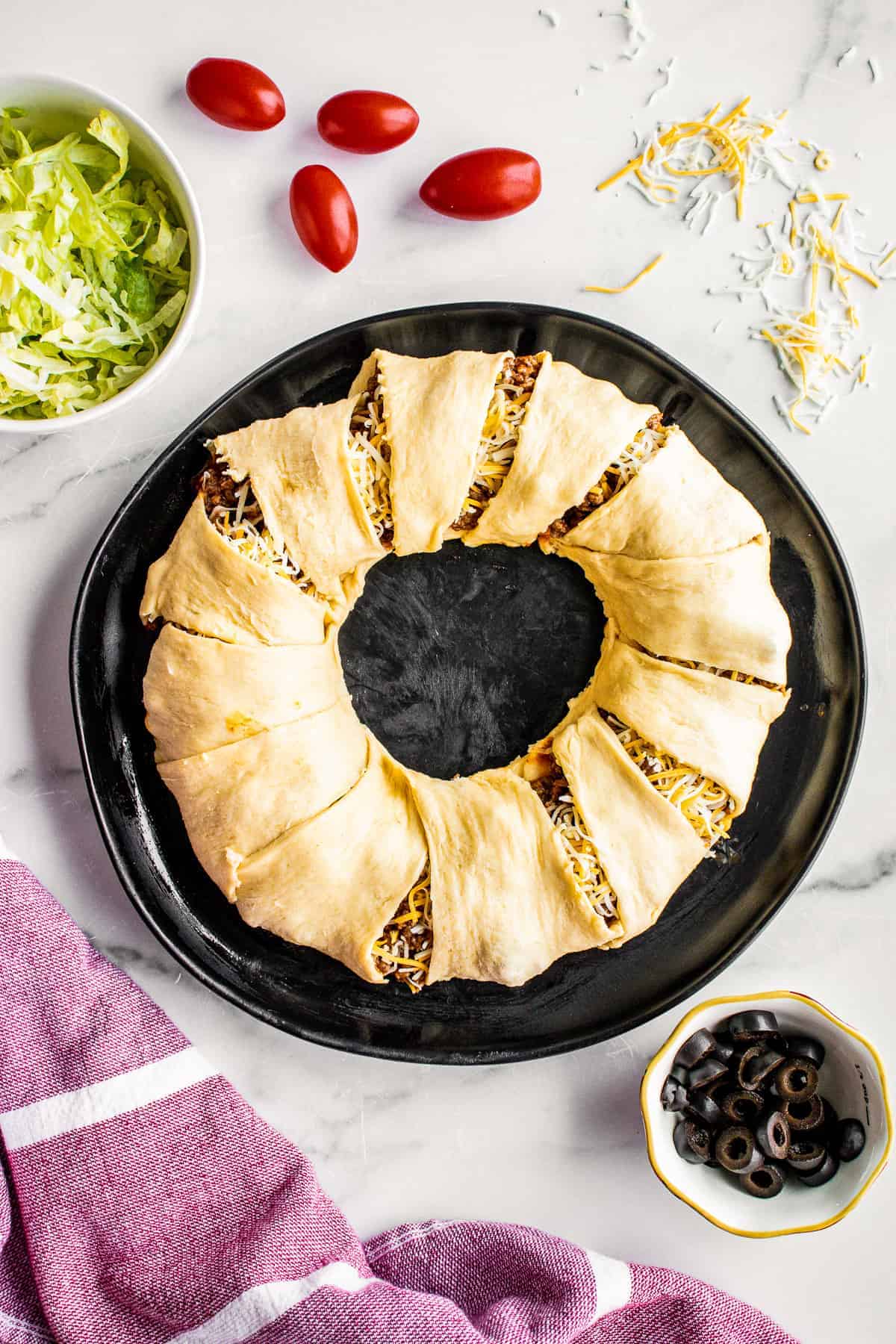 Crescent roll dough in ring filled with taco meat and cheese after folding dough over