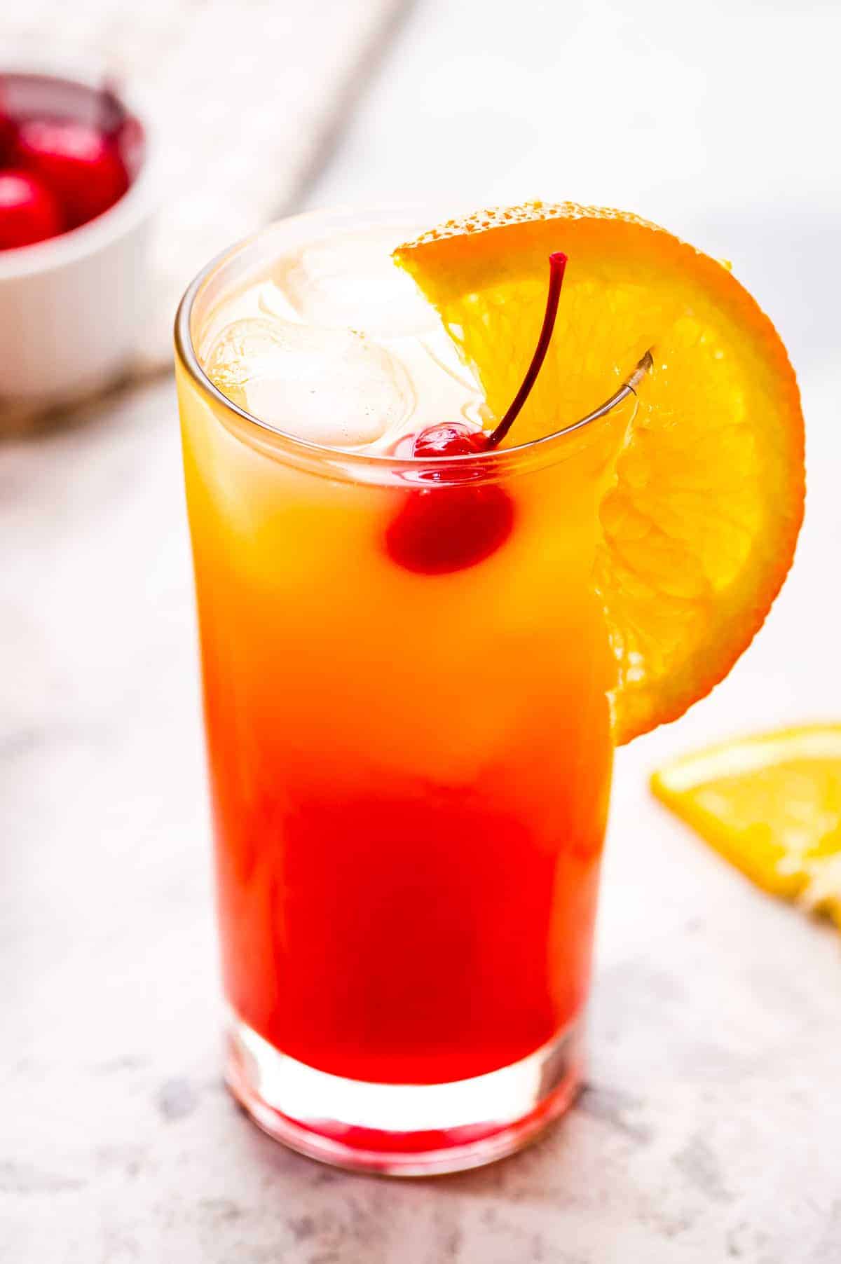 Tequila Sunrise Cocktail in a high ball glass with orange slice garnish