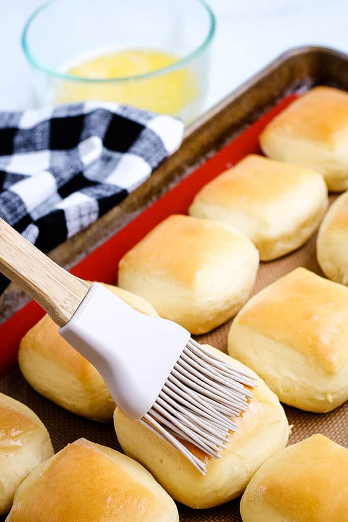 Brushing homemade Texas Roadhouse Rolls with butter