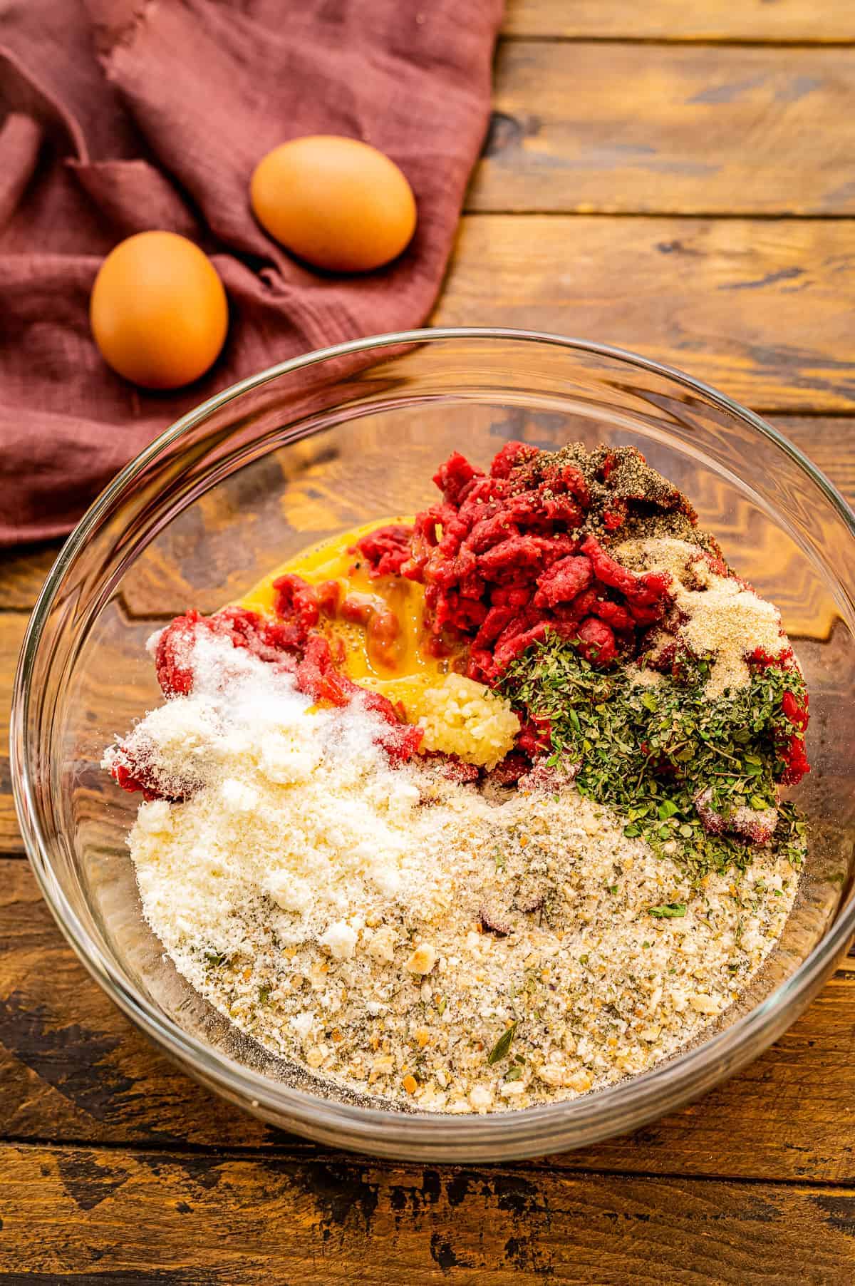 Glass bowl with ingredients in it to make meatballs before mixing