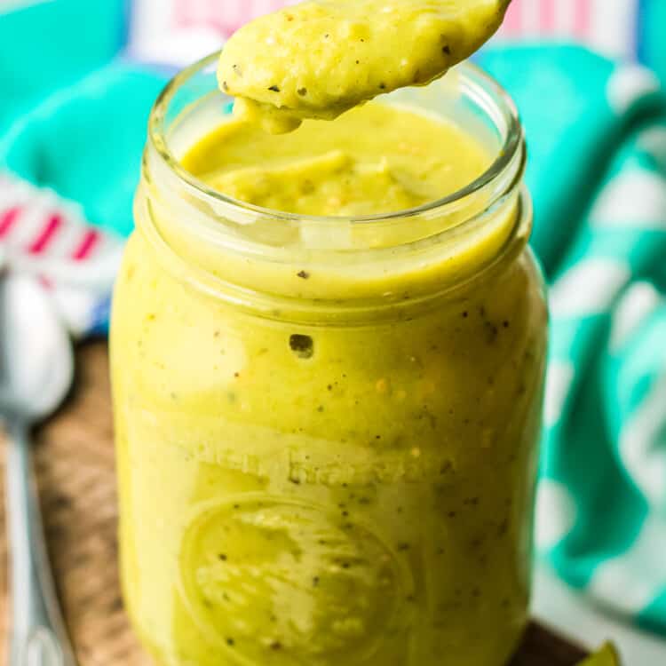 Jar with creamy avocado salsa in it and a spoonful above the jar