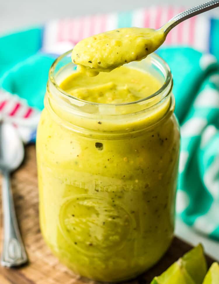 Jar with creamy avocado salsa in it and a spoonful above the jar