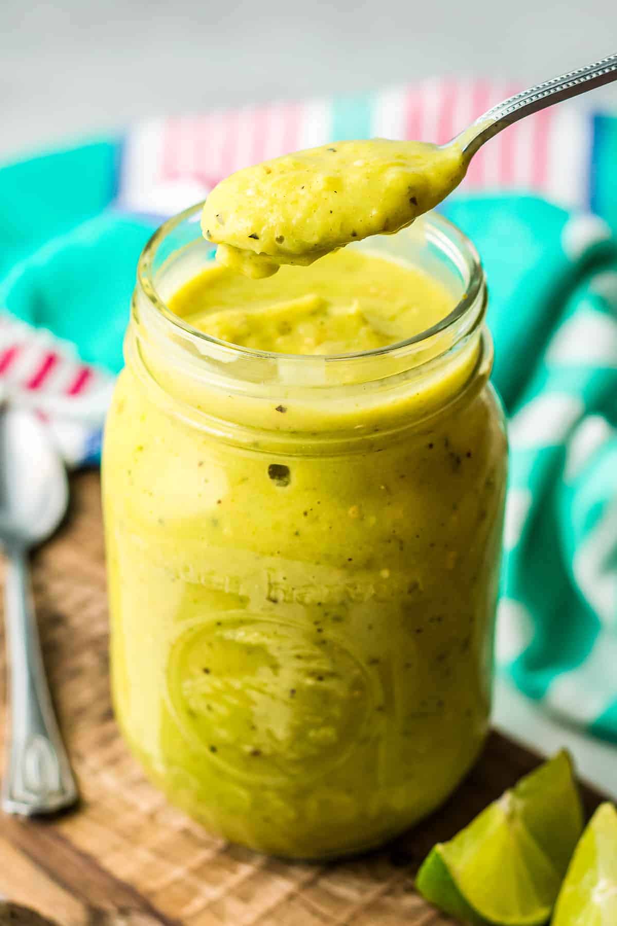 Jar with creamy avocado salsa in it and a spoonful above the jar