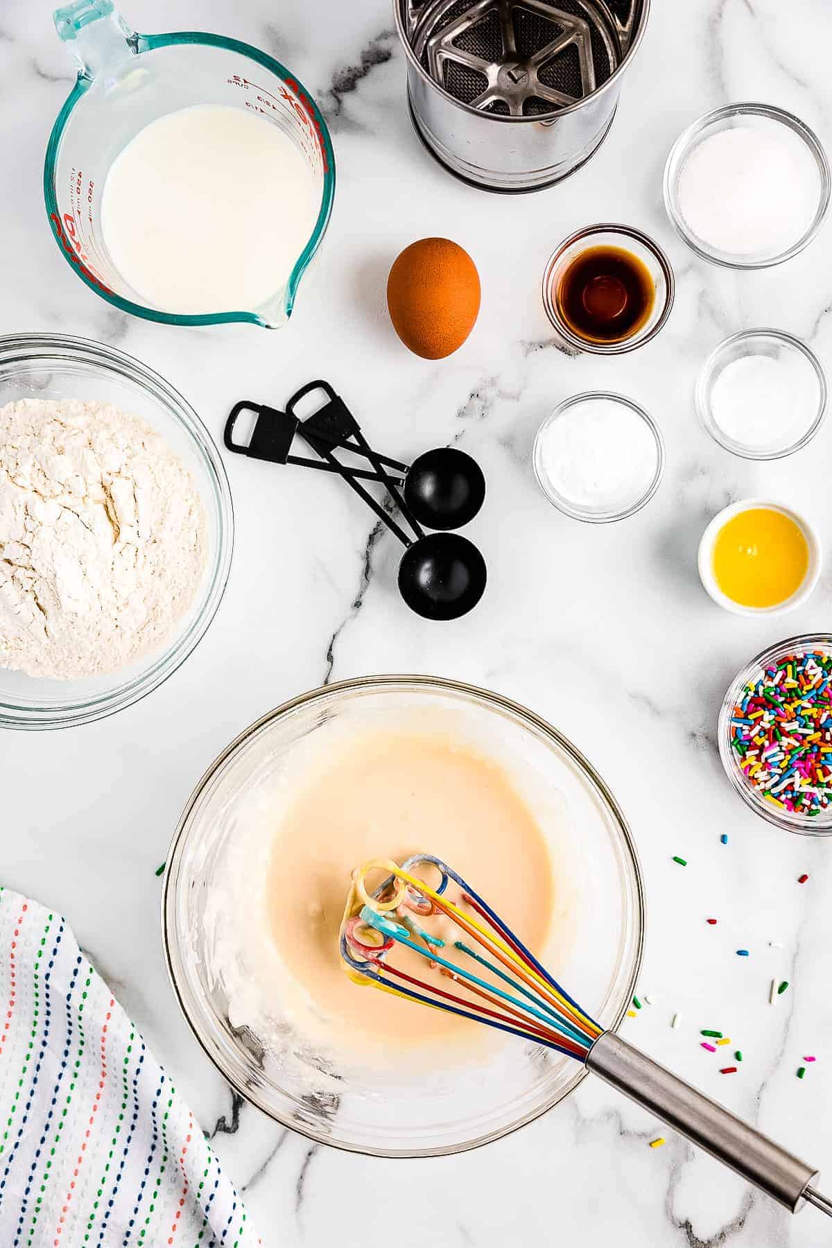 Ingredients in glass bowl mixed up to make frosting for funfetti pancakes