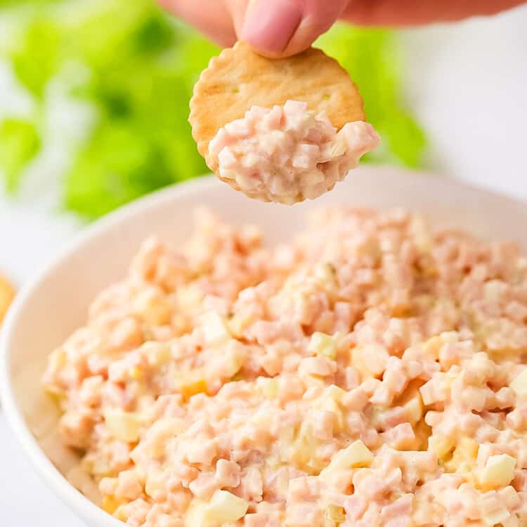 Cracker dipping into a bowl of ham salad