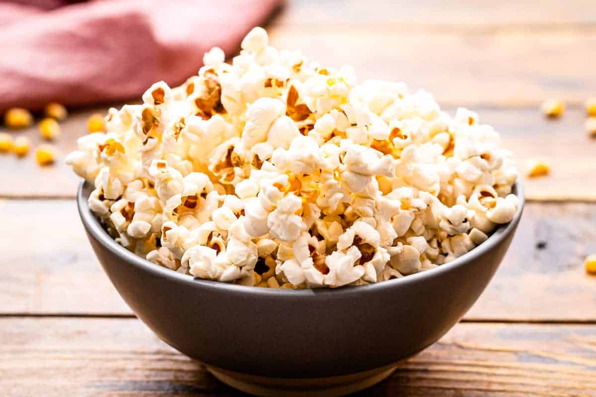 A bowl of popcorn sitting on a wooden background