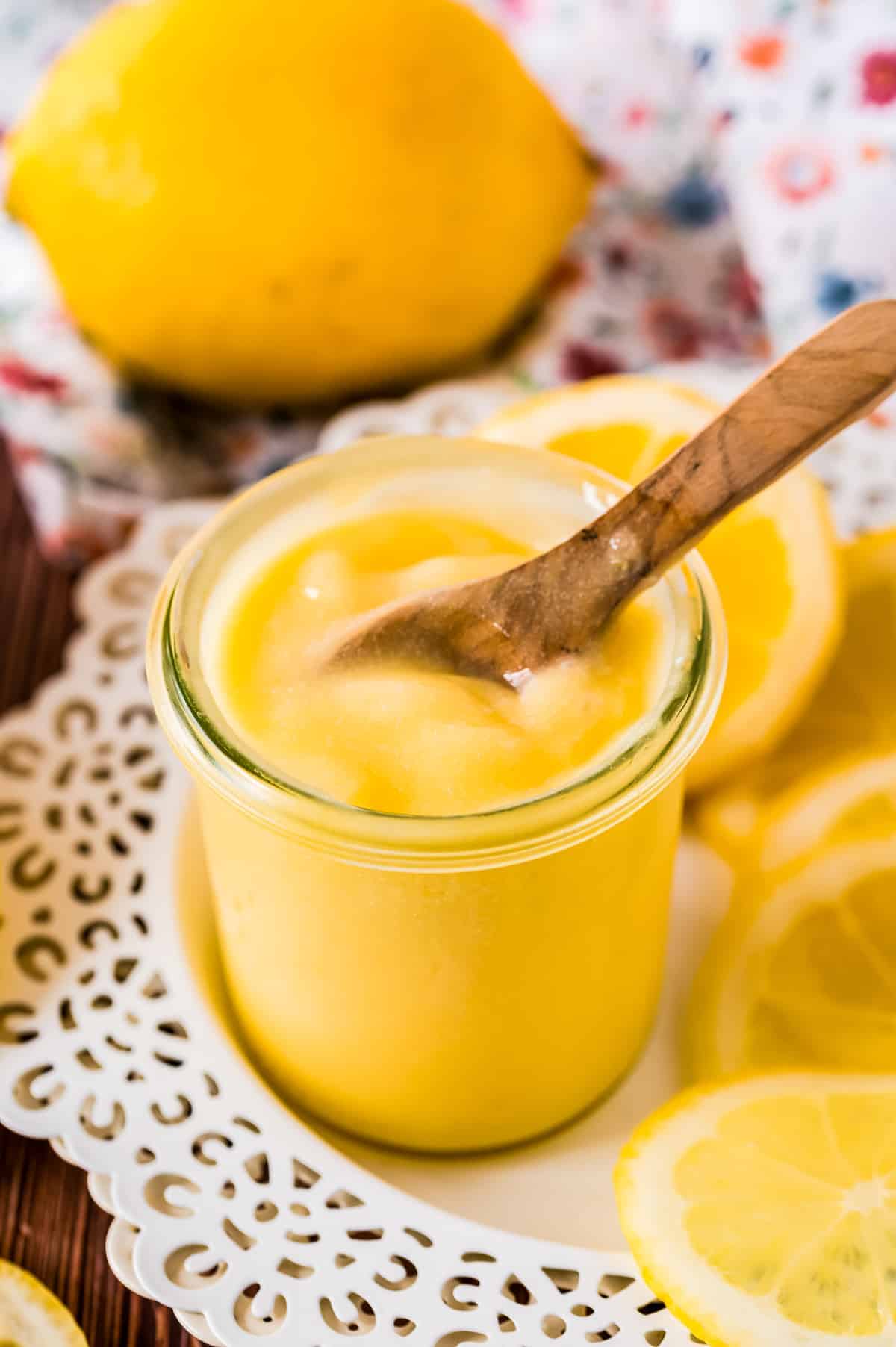 Lemon Curd in a small glass jar with small wooden spoon