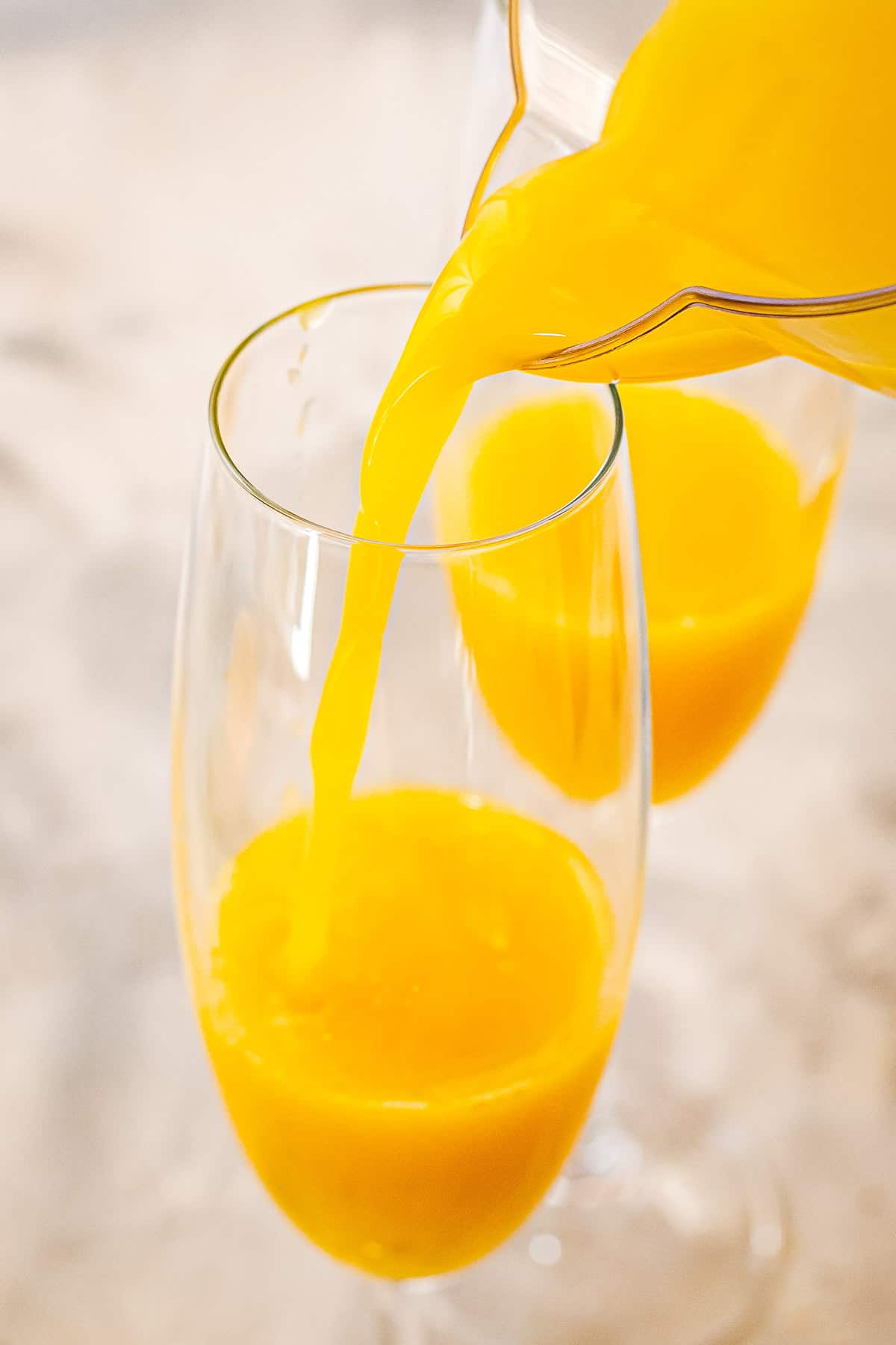 Pouring orange juice into a champagne flute