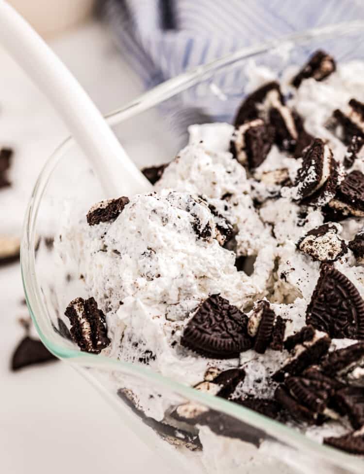 A spoon taking Oreo Salad out of glass bowl