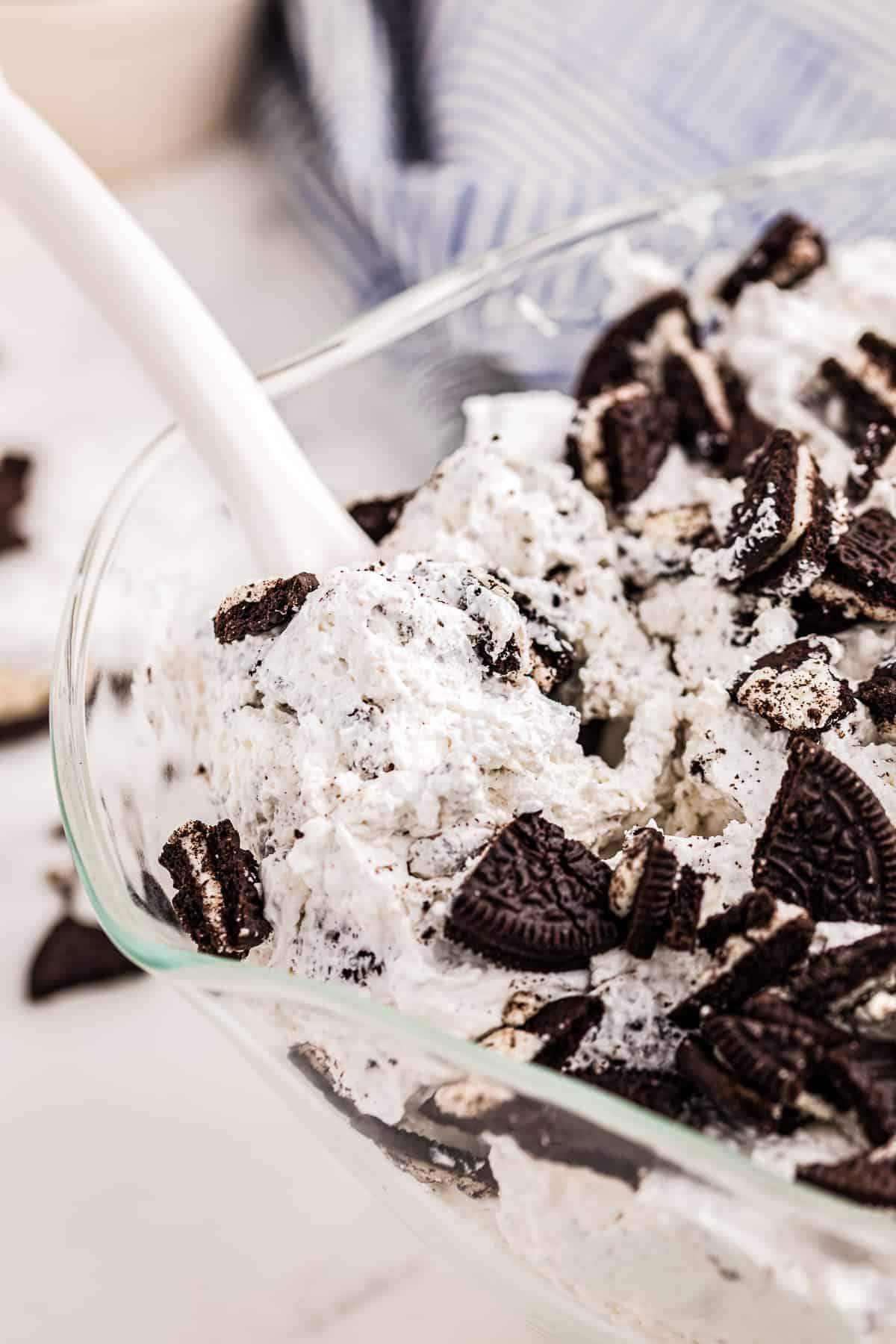 A spoon taking Oreo Salad out of glass bowl