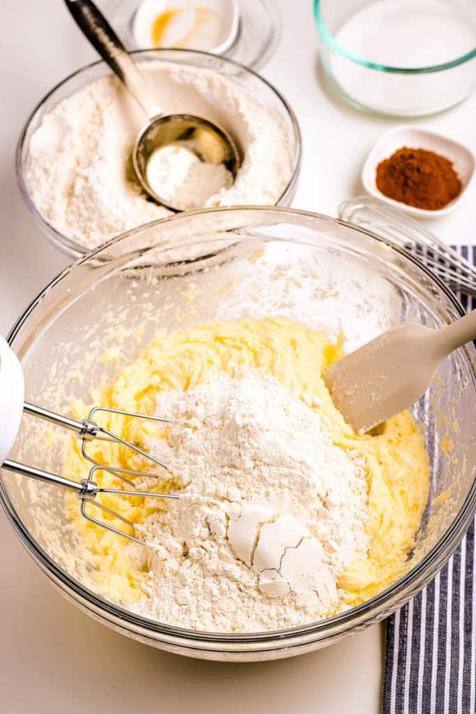 Glass bowl with creamed mixture and flour on top before mixing