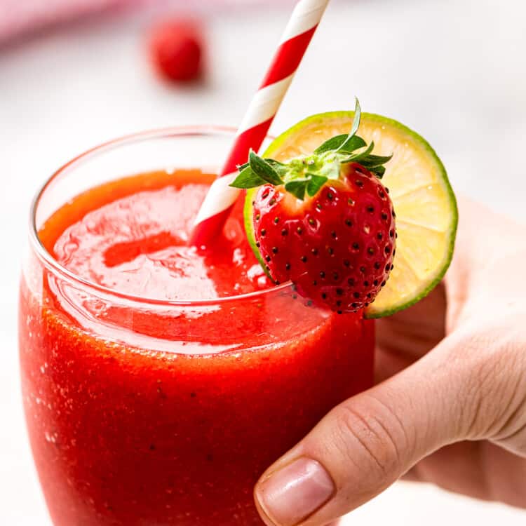 Hand holding a glass with frozen strawberry daquiri