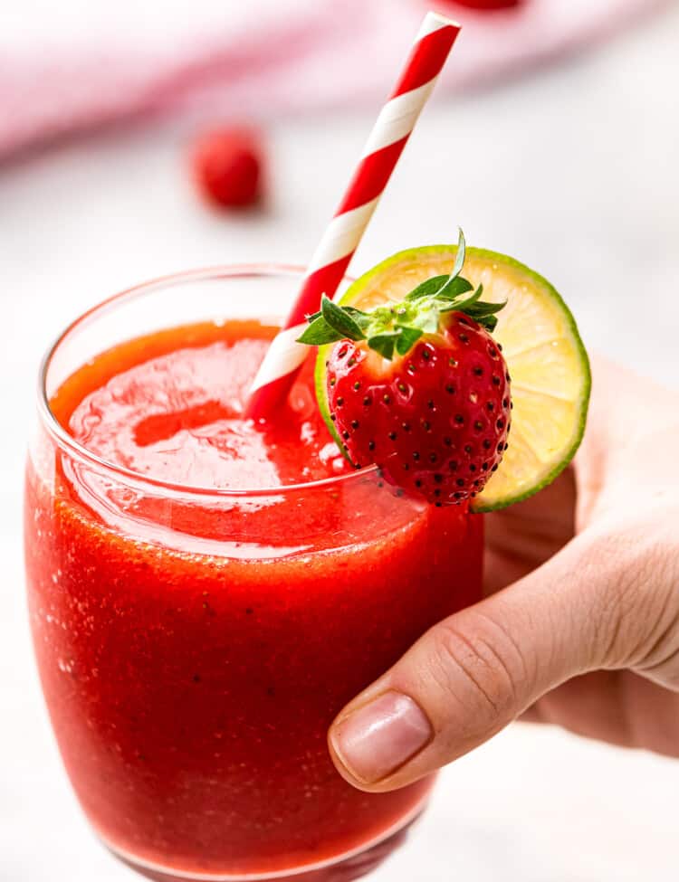 Hand holding a glass with frozen strawberry daquiri