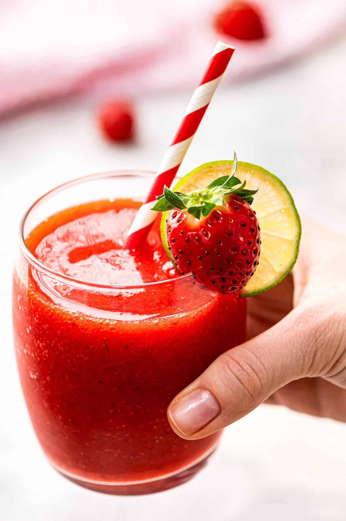 Hand holding a glass with frozen strawberry daquiri