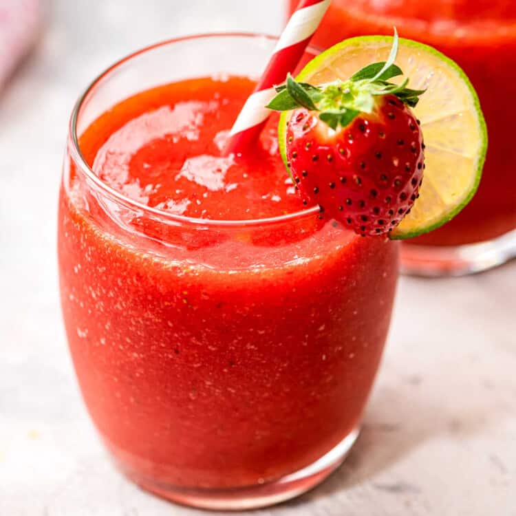 Close up of a glass of Frozen Strawberry Daquiri garnished with lime wheel and strawberry
