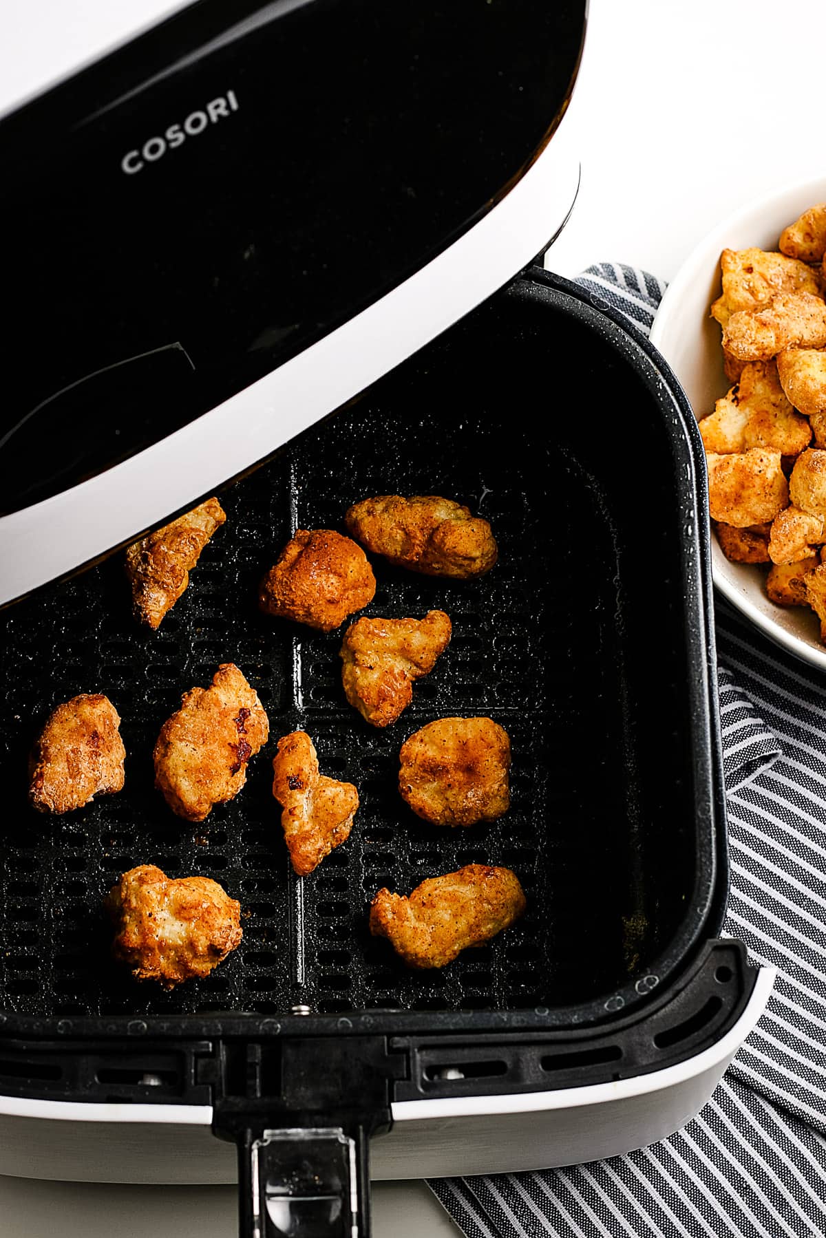 Air Fryer Basket with popcorn chicken in it