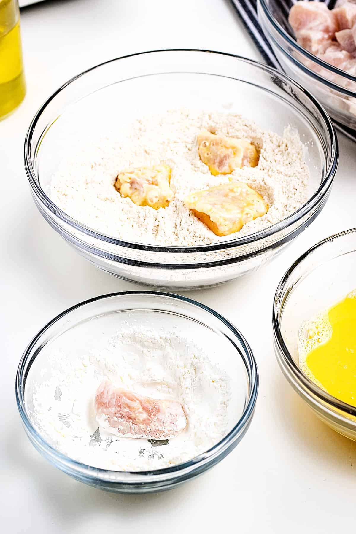 Coating chicken pieces in cornstarch in glass bowl