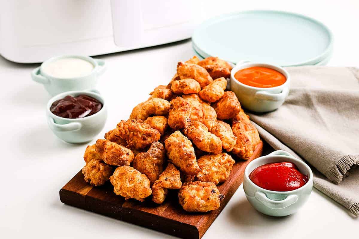 Wooden cutting board with popcorn chicken on it