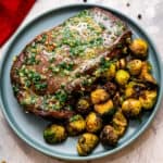 Closely cropped steak with garlic butter topping on a blue plate