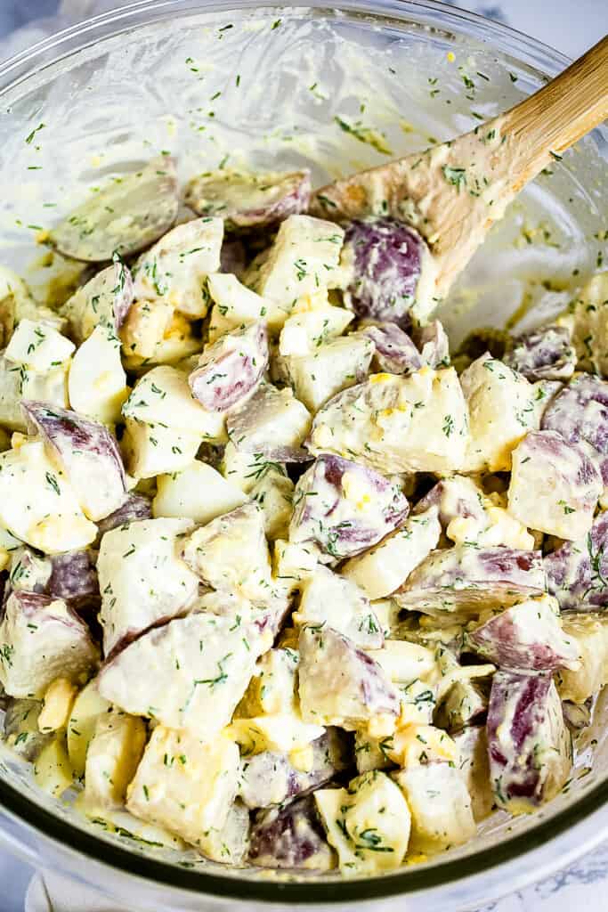 Glass bowl with ingredients for dill potato salad after mixing