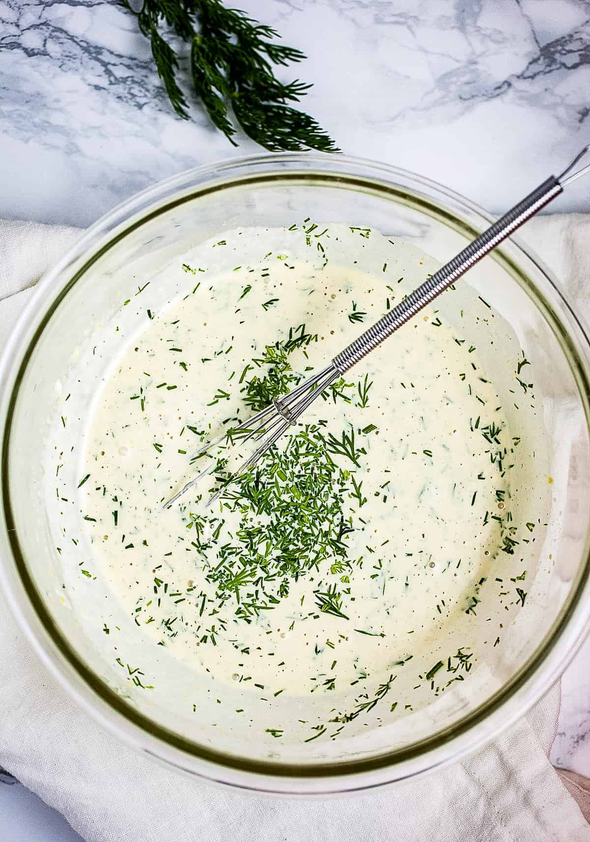 Overhead image of glass bowl with dressing for dill potato salad