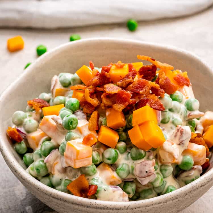 Pea Salad in a bowl topped with crumbled bacon