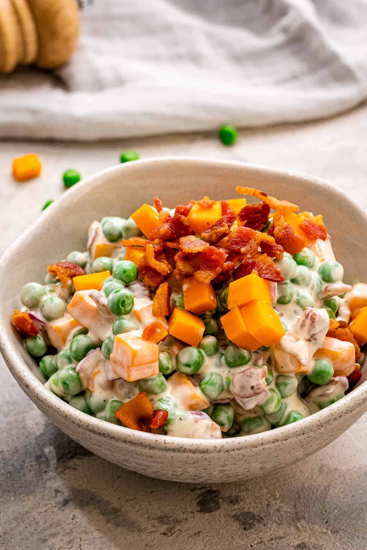 Pea Salad in a bowl topped with crumbled bacon