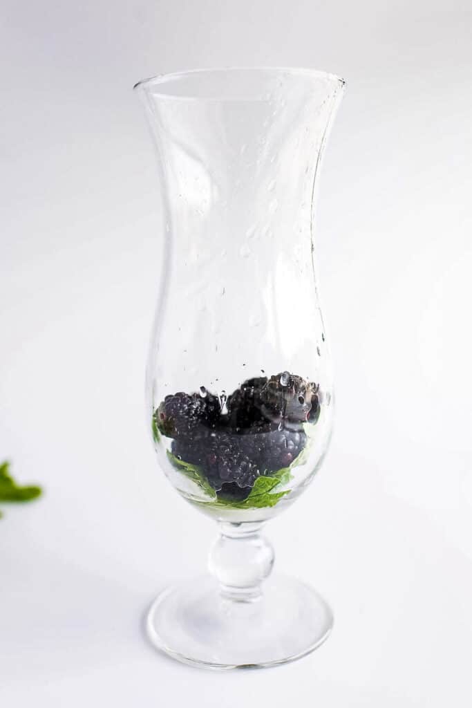 Tall glass with blackberry, mint leaves, lemon and lime juice