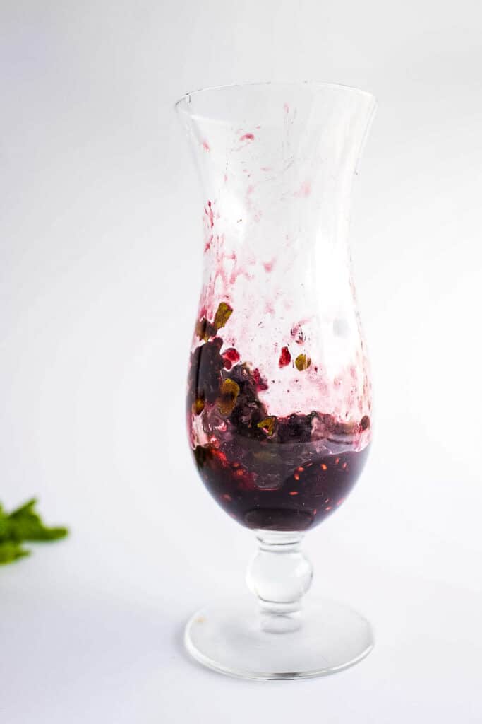 Tall glass with with muddled blackberry mixture for mojitos
