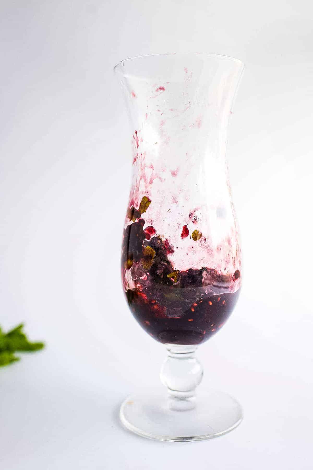 Tall glass with with muddled blackberry mixture for mojitos