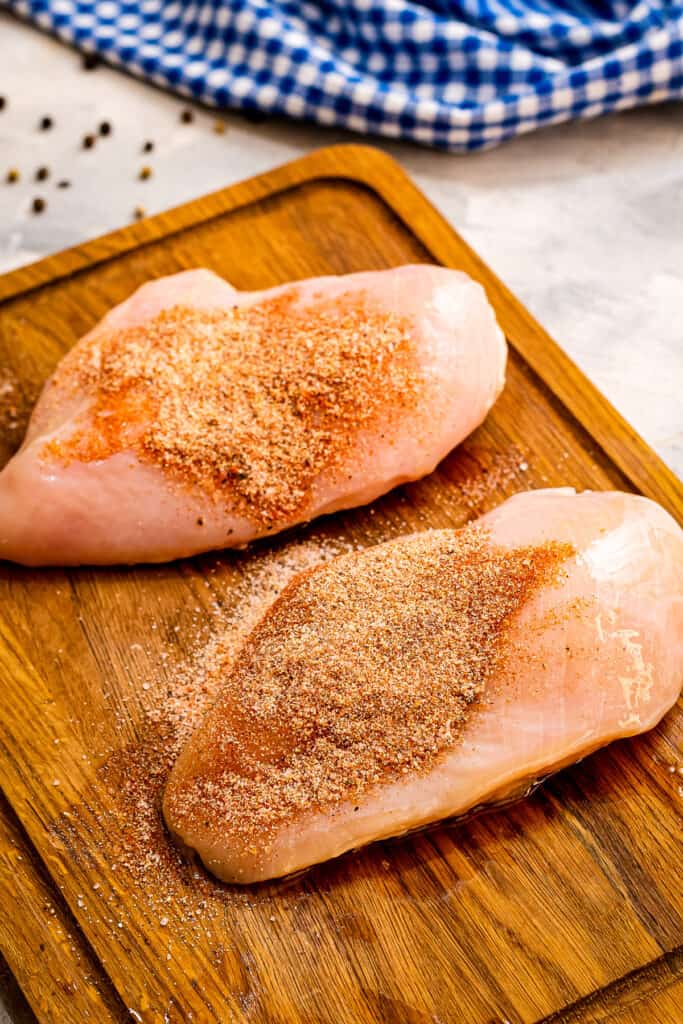 Chicken Breasts with seasonings on a wooden cutting board