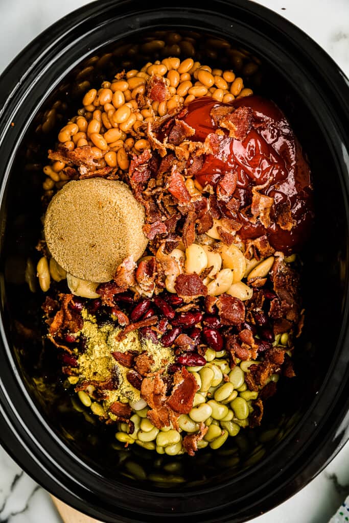 Overhead image of sauce, brown sugar plus beans in crock pot