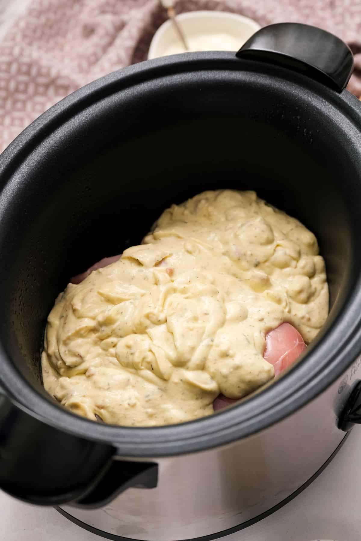 Chicken breasts covered with cream mixture in crock pot