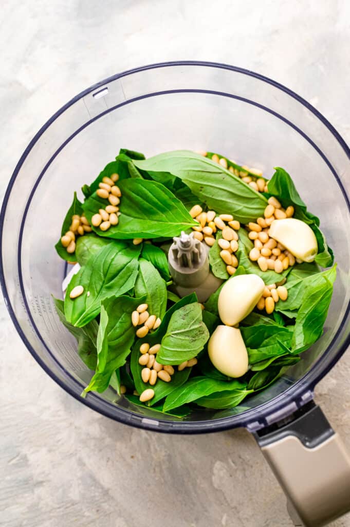 Food processor with ingredients for fresh pesto