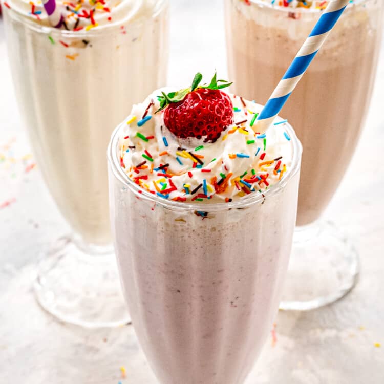 Vanilla, strawberry and chocolate milkshakes with whipped cream and sprinkles