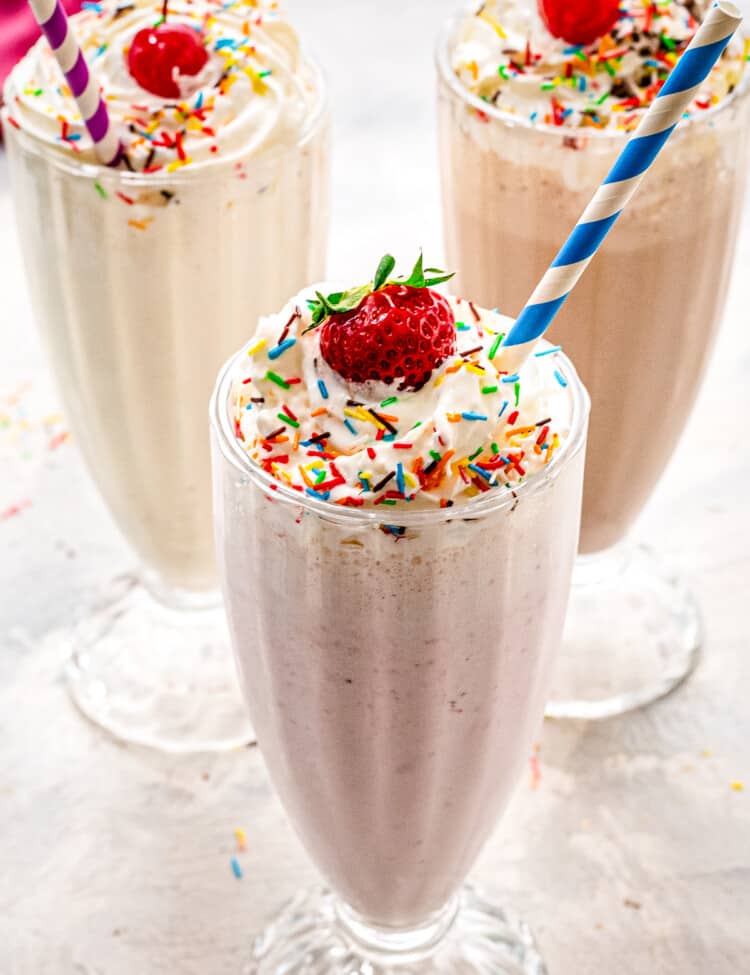 Vanilla, strawberry and chocolate milkshakes with whipped cream and sprinkles