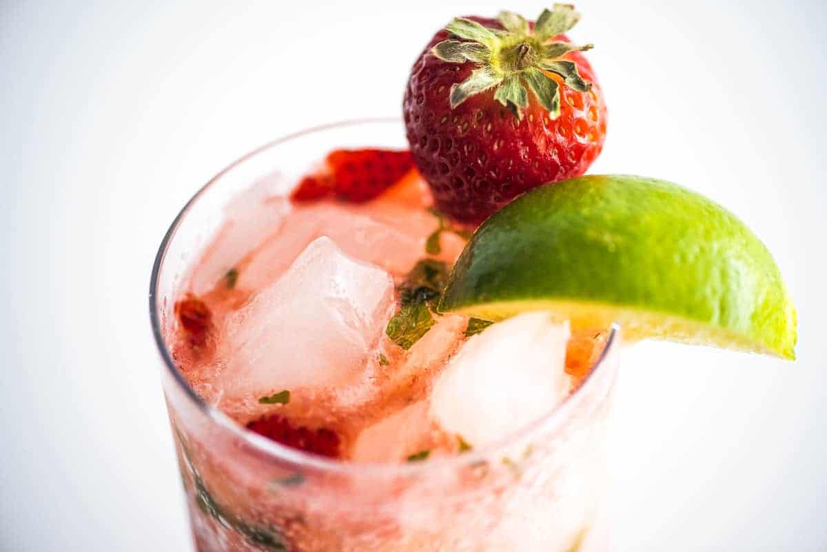 Top view of glass garnished with strawberry and lime with mojito