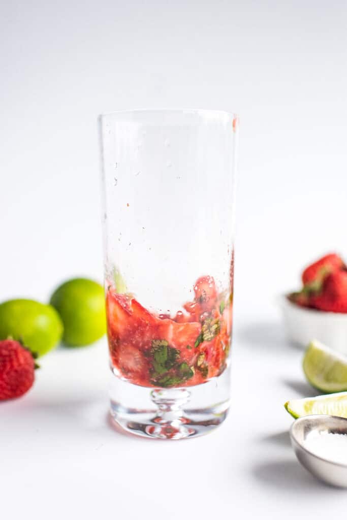 Muddled ingredients in glass for strawberry mojito