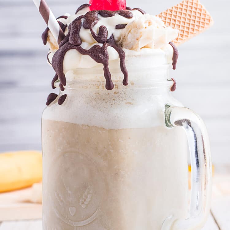 Banana Milkshake in a mason jar topped with chocolate syrup, maraschino cherry and wafer